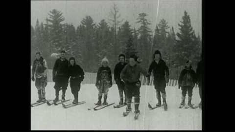 CIRCA 1930s - Boys in the 1930s play on their skis in the snow.