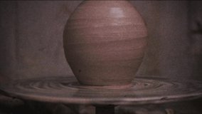 Vintage effect. The potter makes a jug of clay. Family video archive. Retro. Camera 8 mm. Old film. Ceramist. A man makes a vase on a potter's wheel. Handwork. Pottery.  Clay dishes