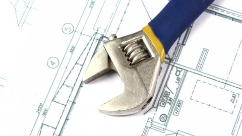 Blue and yellow adjustable wrench isolated on building plan, scheme, close up, rotation