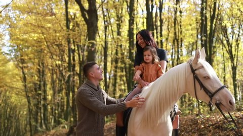 Happy dad teaches horse riding to daughter and wife, happy family