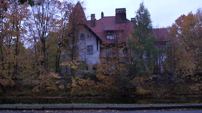 Beautiful house on the banks of the river in autumn, cars passing