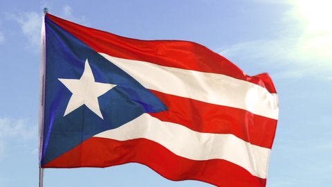 Slow motion of Puerto Rico country flag fluttering on the flagpole outdoors under clear sky