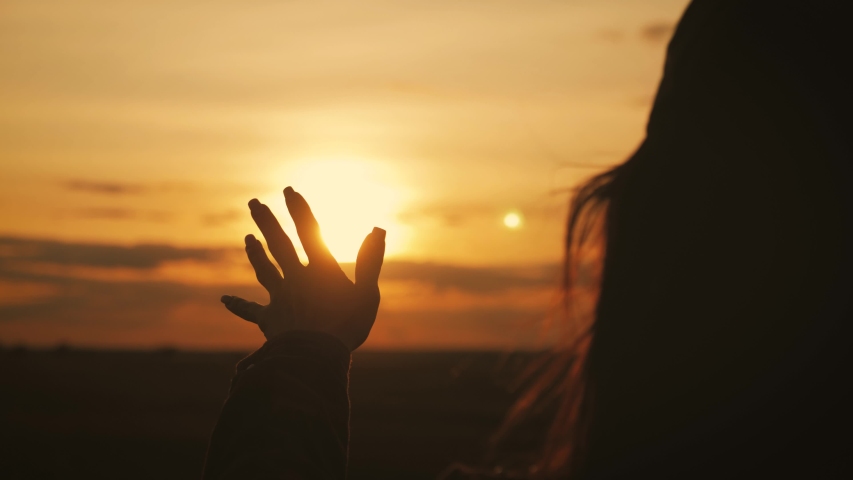 Girl looks at the sun through her hand at sunset. | Shutterstock HD Video #1039299464