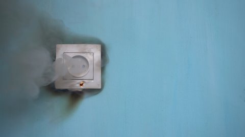Apartment fire is caused by electrical outlet faults. Burnt and damaged electric plug socket from overload short circuit. 