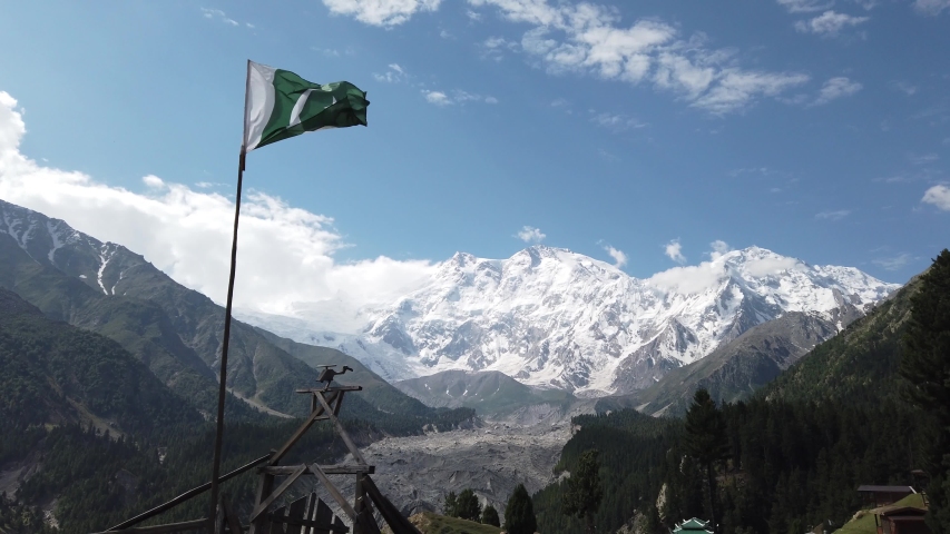Waving Pakistani Flag at Fairy Meadows with with at the background Nanga Parbat Mountain locally known as Diamer, is the ninth highest mountain in the world at 8,126 metres above sea level.  Royalty-Free Stock Footage #1039322915