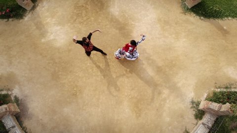 Aerial view from drone of man and woman dancing flamenco in park. Spanish people and traditional dance in Andalusia, Spain. Dancers performing traditional show in park. Couple and music arts