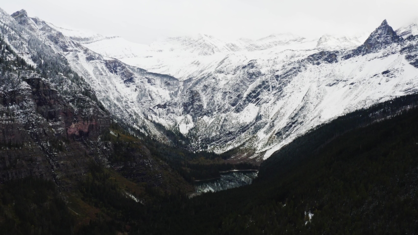 Aerial view of Glacier National Park, breathtaking landscapes of Montana, snowy mountain peaks and endless green forest, moody shoots of nature
