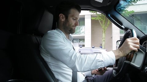 A middle aged caucasian man distracted driving while using a mobile device stops his vehicle suddenly to avoid an accident. - HD 24FPS