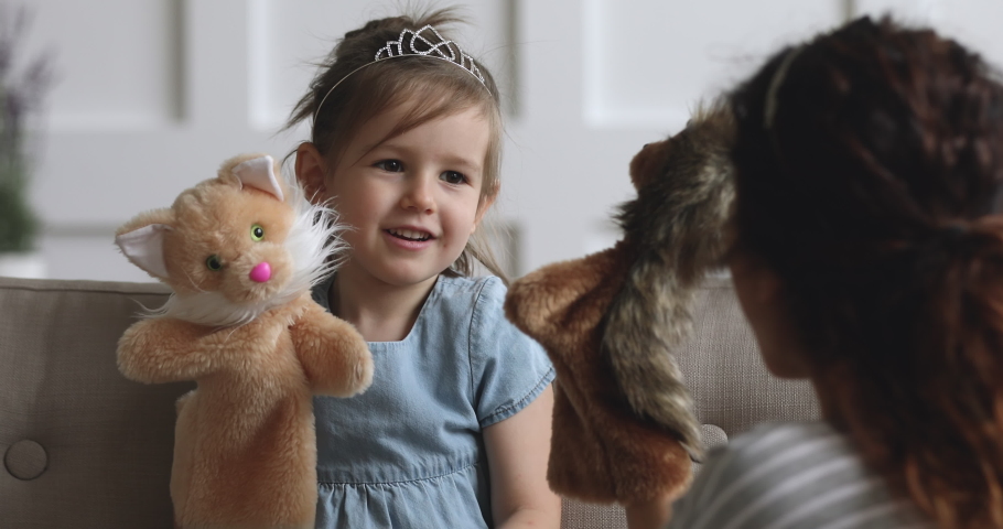 Cute small kid girl princess wear crown holding puppet toy playing with mother, adorable little child daughter with rag doll on hand having fun enjoying fairy tale talking to mom babysitter at home Royalty-Free Stock Footage #1039337831