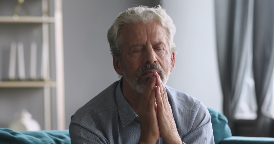Elderly senior grandfather pray with hope faith at home alone, religious old man catholic christian hold hands together say gratitude worship prayer with eyes closed, older people religion concept Royalty-Free Stock Footage #1039337861