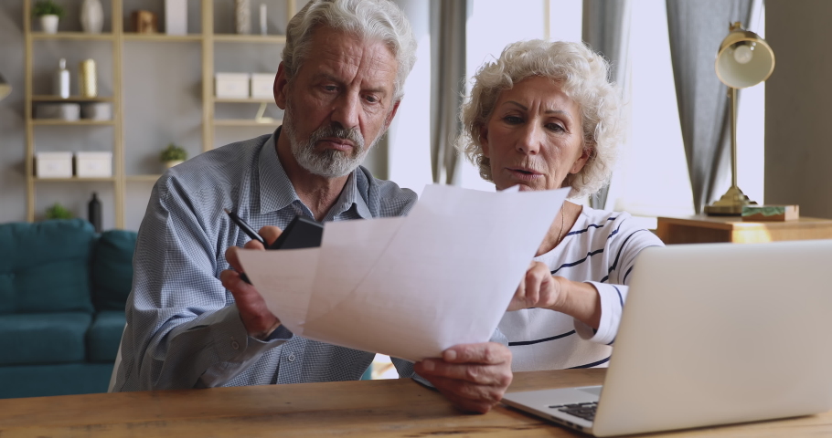 Worried senior retired couple checking calculating bills bank loan payment doing paperwork discuss unpaid debt taxes, stressed old grandparents family look at laptop upset about money problem concept | Shutterstock HD Video #1039337867