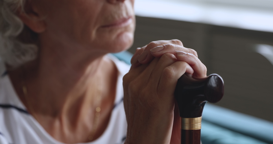 Disabled old senior grandmother holding walking cane stick in hands, sad elderly woman hopeless depressed about health problem injury worried of disease concept alone at home hospital, close up view | Shutterstock HD Video #1039337870