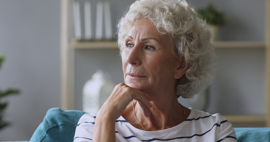 Pensive thoughtful lonely senior lady serious face looking away sitting alone on sofa at home, worried melancholic single old elder woman grandmother waiting thinking of solitude loneliness concept Royalty-Free Stock Footage #1039337873