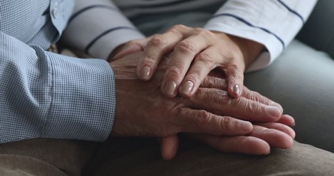 Caring elderly grandma wife holding hand supporting senior grandpa husband give empathy care love, old married grandparents couple together two man and woman hope understanding concept, close up view
