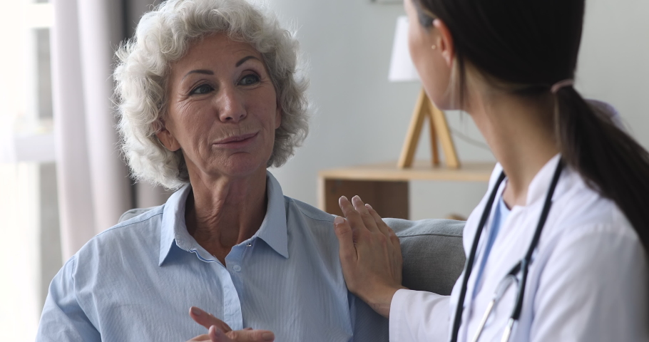 Happy elderly grandma and young woman nurse doctor talk during medical checkup visit, smiling female old senior patient speak to counselor at consultation get support healthcare treatment concept | Shutterstock HD Video #1039338026