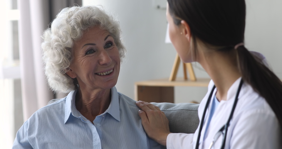 Happy elderly grandma and young woman nurse doctor talk during medical checkup visit, smiling female old senior patient speak to counselor at consultation get support healthcare treatment concept | Shutterstock HD Video #1039338026