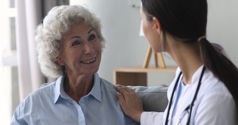 Happy elderly grandma and young woman nurse doctor talk during medical checkup visit, smiling female old senior patient speak to counselor at consultation get support healthcare treatment concept
