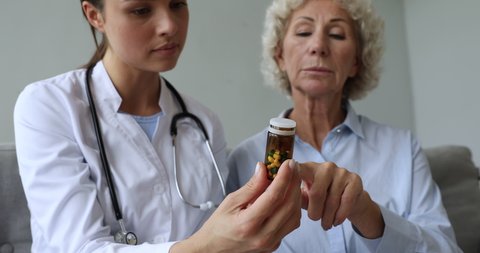 Female doctor pharmacist holding medicine pills bottle explaining prescription to older woman patient prescribing drug at medical consultation, seniors healthcare and pharmacy concept, close up view
