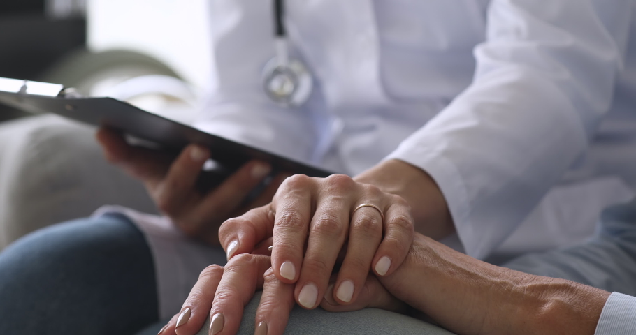 Female nurse doctor wear white uniform hold hand of senior grandmother patient help express empathy encourage tell diagnosis at medical visit, older people healthcare support concept, close up view | Shutterstock HD Video #1039338044