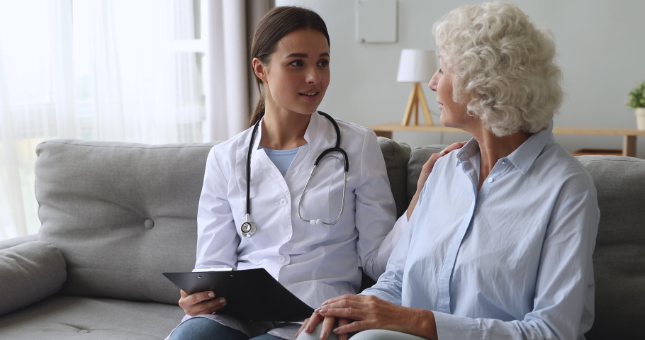 Caring young female nurse caretaker doctor helping talking with senior grandmother patient give support empathy encouraging elderly woman at medical visit, older people healthcare recovery concept Royalty-Free Stock Footage #1039338056