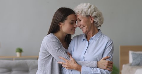 Loving young adult woman daughter hug elderly grandma at home, affectionate two women generation family old mother bonding embrace granddaughter express tenderness care support enjoy reunion concept