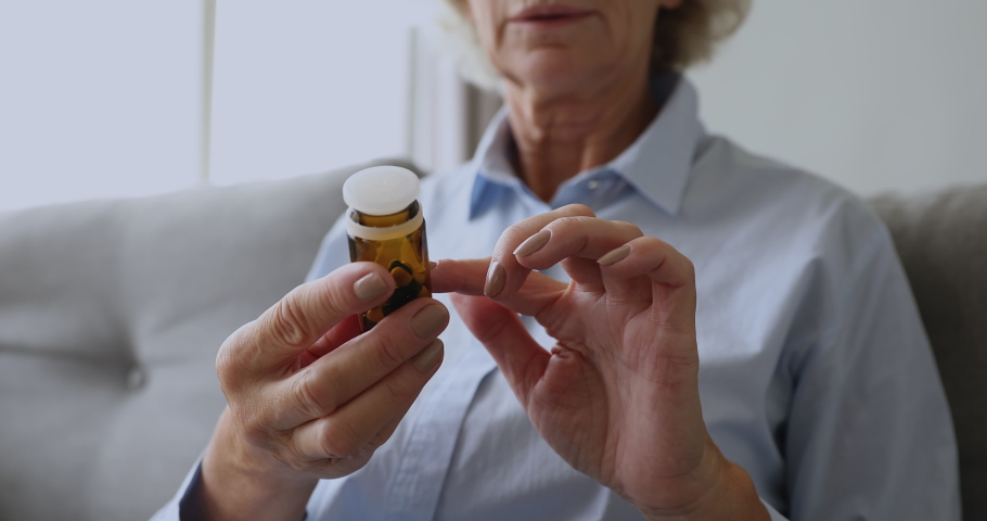 Old senior woman grandma read drug prescription label pour two pills from medication bottle hold painkiller capsules on hand take medicine, elderly people healthcare, pharmacy concept, close up view Royalty-Free Stock Footage #1039338134