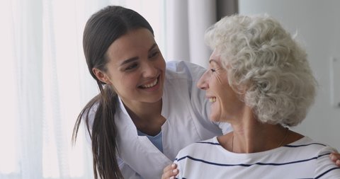 Happy young woman nurse caretaker helping talking with senior grandmother patient give support empathy, female doctor carer having trust conversation with elderly lady, older people homecare concept