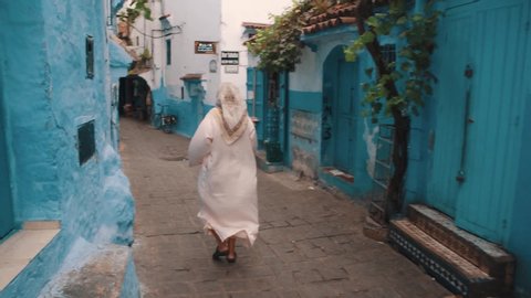 chefchaouen , tanger - tétouan - el houceima / Morocco - 09 27 2019: Old Moroccan woman with traditional clothes walking in a beautiful street in Chefchaouen, Morocco