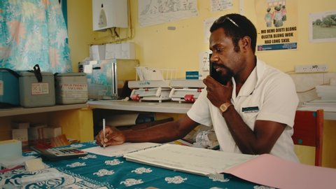 Melsisi, Pentecost Island / Vanuatu - May 10 2019: local village medical nurse doctor sorting out vaccination paperwork at the rural hospital clinic