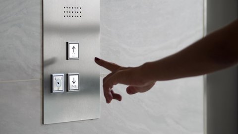 Female Hand Pushing Elevator Button in Office Center or Hotel. Young Woman Pressing Lift Button Down. 4K.