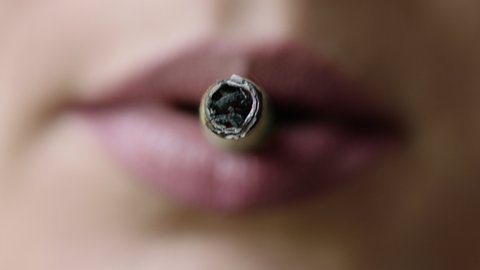 Smoking of joint, Smoking cigarette, close up macro, prores4444, RAW, Arri Alexa mini. Women with pink nude lipstick lights and puff cigarette from natural leaves