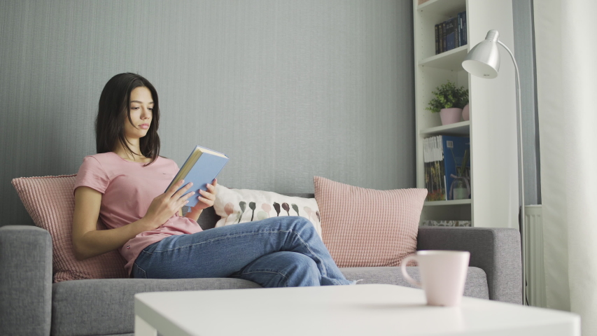 Woman reading a book and realxing on sofa at home