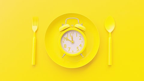 Yellow clock on yellow plate with fork and spoon background, Break time idea concept. The beginning of time 11.45 run fast to 12.00. Timelapse moving fast.