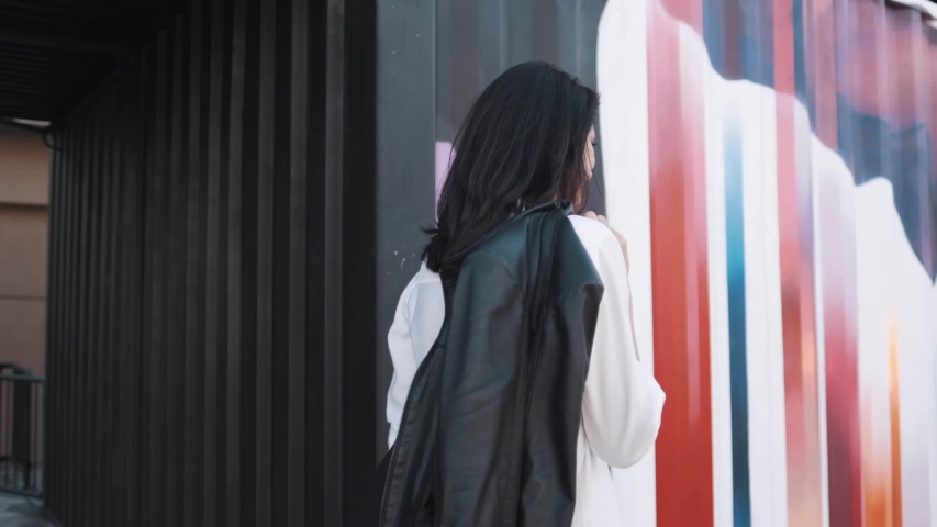 Attractive girl of European appearance walks down the street smiling