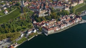 Aerial view of the city Meersburg beside the lake Constance in Germany on a sunny day in autumn, fall. Pan to the left and tilt up beside the old town.