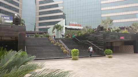Gurgaon, India - circa 2019: Panning up shot showing modern galss buildings and stairs going up to the shops in Gurgaon india asia. Shows the high profile residential, office real estate in premium