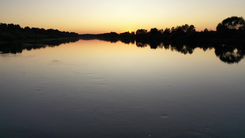 Flight over the river surface at sunset
