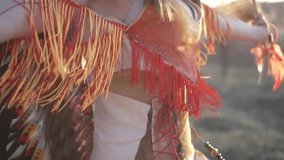 Ritual dance on the sunsett of beautiful girl in native American Indian headdress and costume with colorful make-up with indian grass in her hands. 