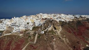 Aerial drone video of traditional and picturesque village of Oia in volcanic island of Santorini, Cyclades, Greece