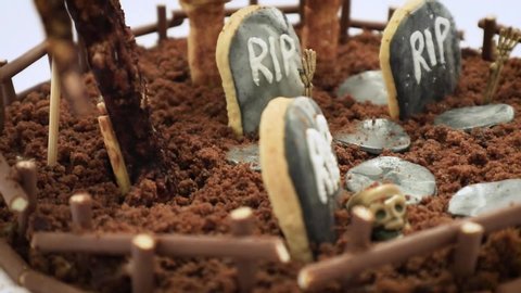 Halloween cemetery cake with creepy decorations, tombstones, bones, bats, dry tree on white background 