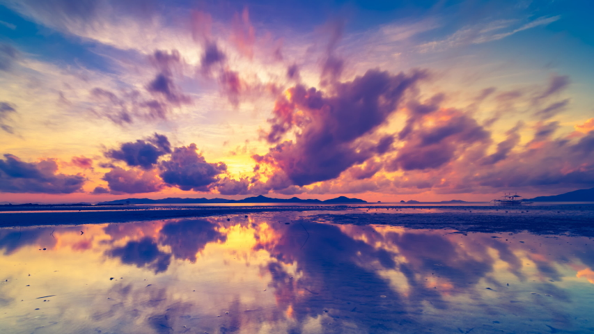 Amazing boundless coloured evening clouds float lit by setting sun light reflecting in ocean against hill silhouettes at sunset time lapse. Concept travel tropical nature landscape sunset. Thailand 4K