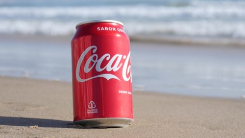 ALICANTE, SPAIN - OCTOBER 09, 2019: A Can of Coca-Cola drink left on the Sea Beach on the Sand