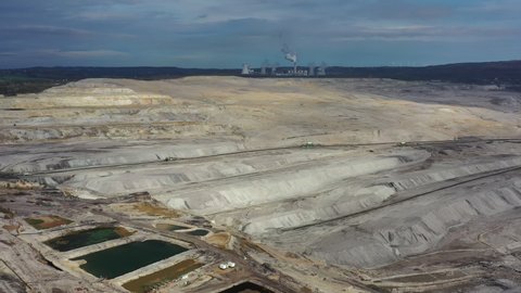 Aerial view of open pit brown coal mine (lignite coal quarry), steaming chimney and cooling towers of coal power plant in background - landscape panorama of Turow from above, Bogatynia, Poland, Europe