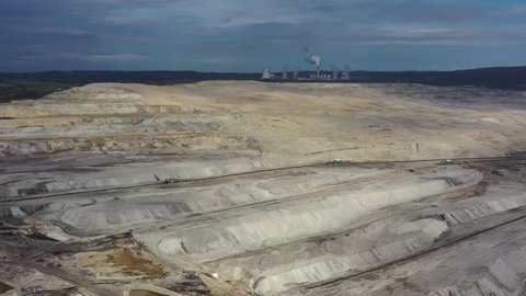 Aerial view of open pit brown coal mine (lignite coal quarry), steaming chimney and cooling towers of coal power plant in background - landscape panorama of Turow from above, Bogatynia, Poland, Europe