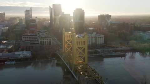 Aerial drone right parallax of Tower Bridge and Downtown Sacramento, CA, including Old Sacramento & State Capitol in background during sunrise.