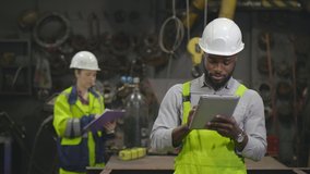 African industrial inspector using digital tablet while doing inventory and discussing production with his caucasian colleague - Powered by Shutterstock - Get 15% off with code: PIKWIZARD15