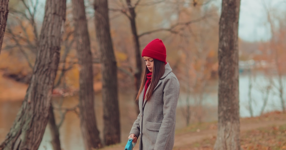 Beautiful young woman walks along the path, walks with a pet. Little puppy pulls the mistress by the leash.