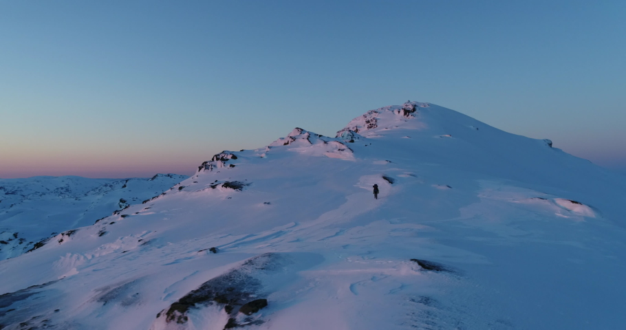 DRONE; Man Climbing Snowy Montain while the Sun Rises