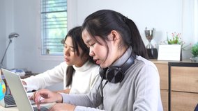 beautiful portrait of Asian student learning online, viewing listening watching video tutorials with silver laptop computer and headphones on table at home,Education studying in technology concept
