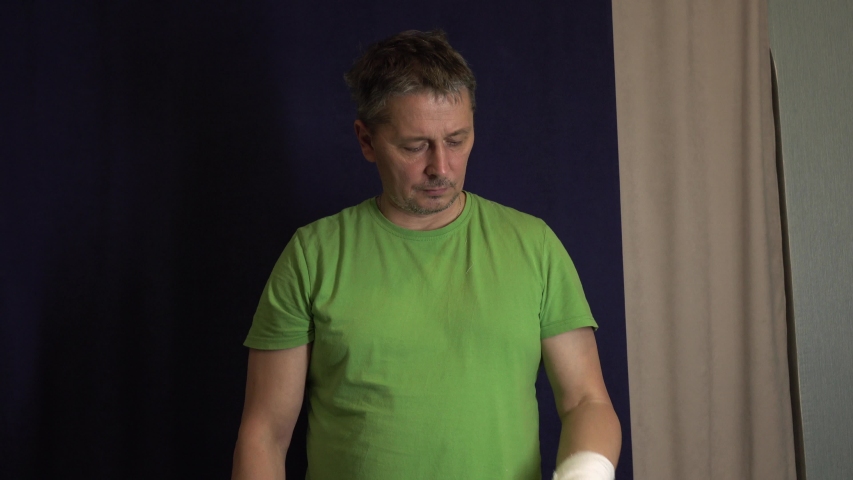 A man scratches his arm in a cast . Man